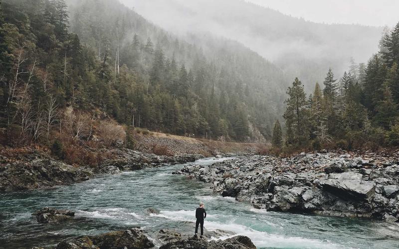 Original photo of a misty river gorge with a hiker standing on the rocks, circled by the cleanup brush