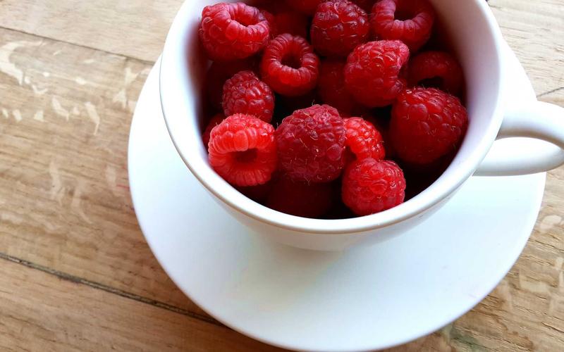 AI-generated overhead image of raspberries in a white cup