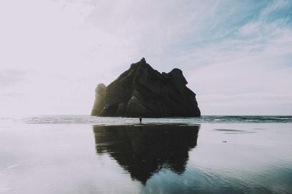 Training image: a sea stack mirrored on a misty tidal beach